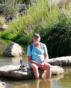 Besucher sitzt auf einem Stein am Wasser der Jagst