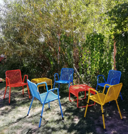 Bunte Gartenstühle im Schatten unter Bäumen